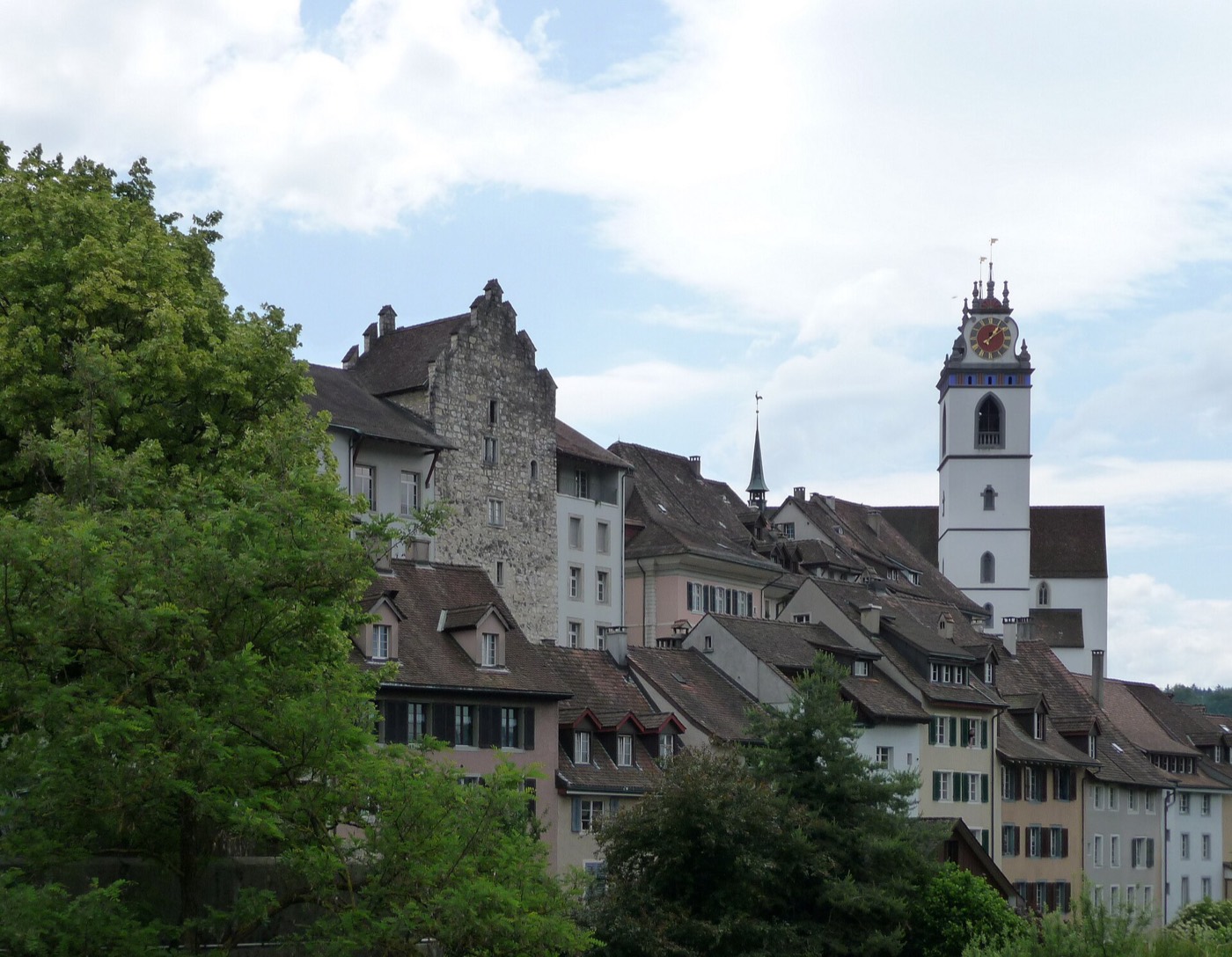 Silhouette der Aarauer Altstadt: links der hohe Steinturm des Schlössli aus grob behauenen Steinen, rechts der weisse Turm der Stadtkirche mit Uhr, dazwischen dicht gestaffelte Ziegeldächer