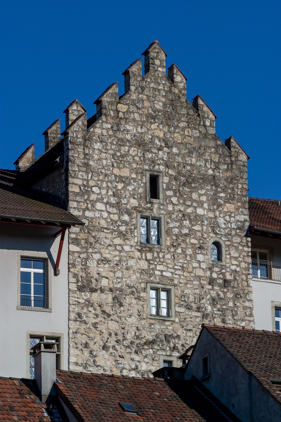 Der Turm Rore in Aarau: ein hoher Bruchsteinbau mit Treppengiebel und kleinen Fenstern, umgeben von niedrigeren Ziegeldächern